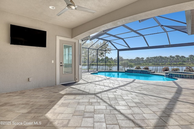 view of pool with ceiling fan, a pool with connected hot tub, a water view, glass enclosure, and a patio