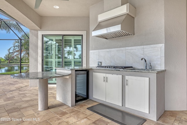 exterior space with exterior kitchen, a water view, glass enclosure, and beverage cooler