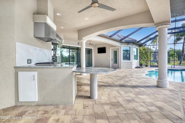 view of patio / terrace with a lanai, an outdoor pool, a ceiling fan, and exterior kitchen