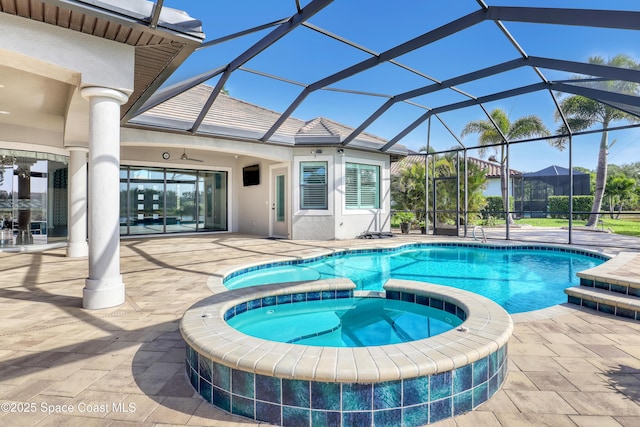 view of pool with a patio, a pool with connected hot tub, a ceiling fan, and glass enclosure