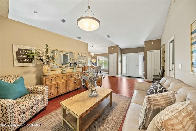 living room featuring visible vents, wood finished floors, and vaulted ceiling