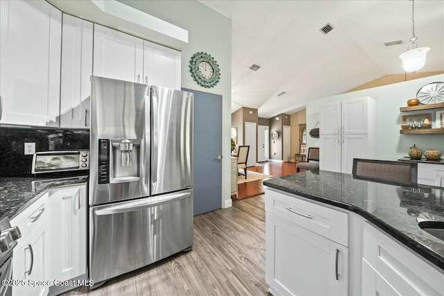 kitchen featuring visible vents, stainless steel fridge, light wood finished floors, white cabinetry, and vaulted ceiling