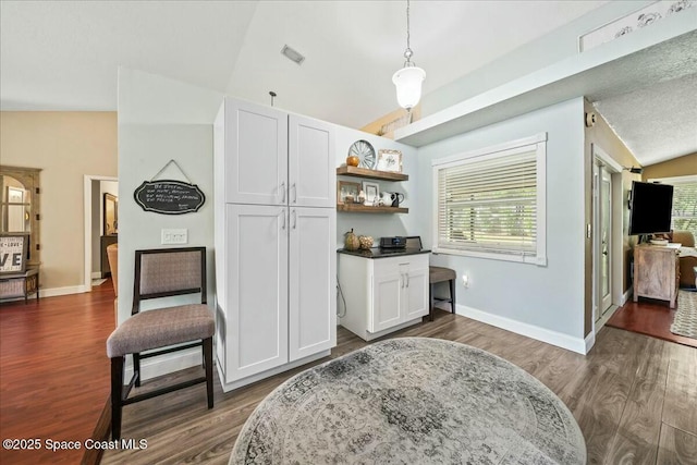 living area with baseboards, visible vents, vaulted ceiling, and dark wood finished floors