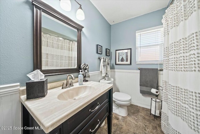 bathroom with vanity, toilet, wainscoting, and a shower with curtain