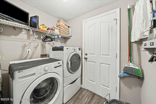 laundry area featuring a textured ceiling, wood finished floors, laundry area, and washer and clothes dryer