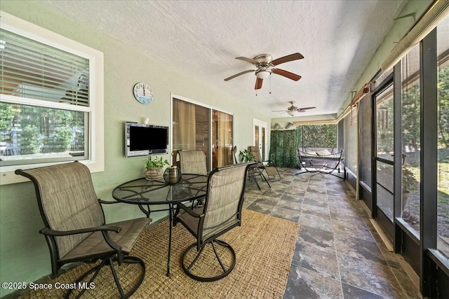 sunroom / solarium with outdoor dining area and ceiling fan