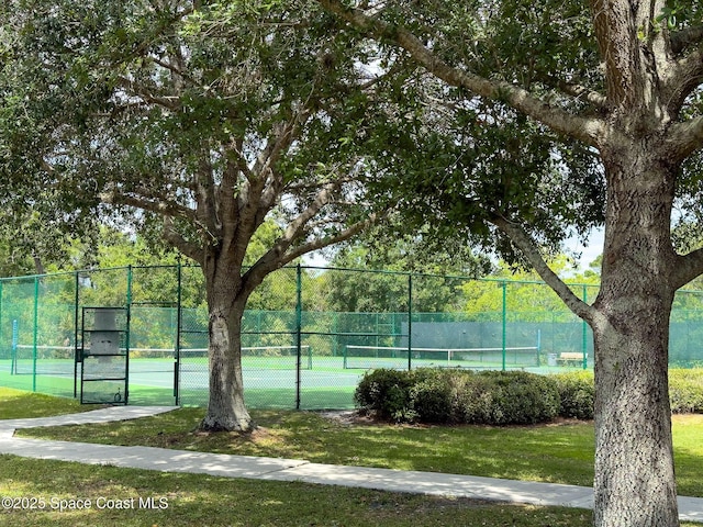 view of tennis court with fence and a lawn