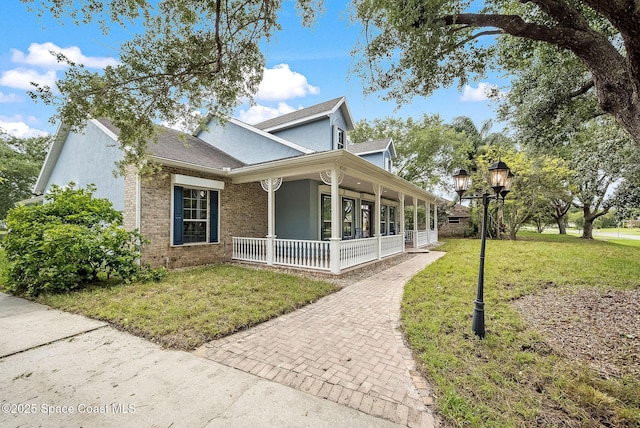 view of property exterior with a porch, brick siding, stucco siding, and a lawn