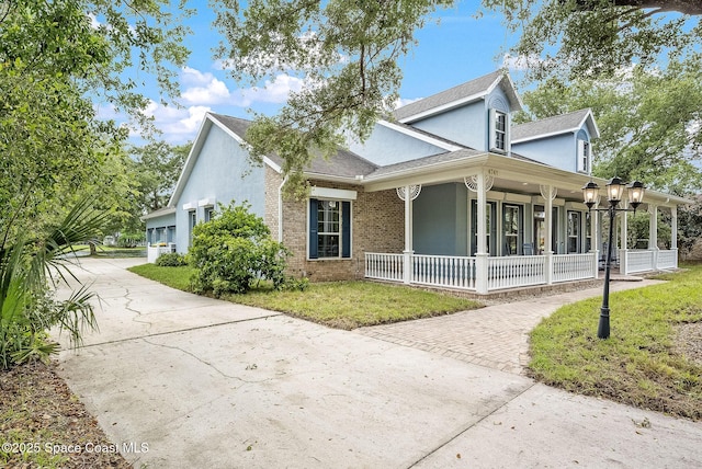 view of property exterior featuring concrete driveway, stucco siding, brick siding, a yard, and covered porch