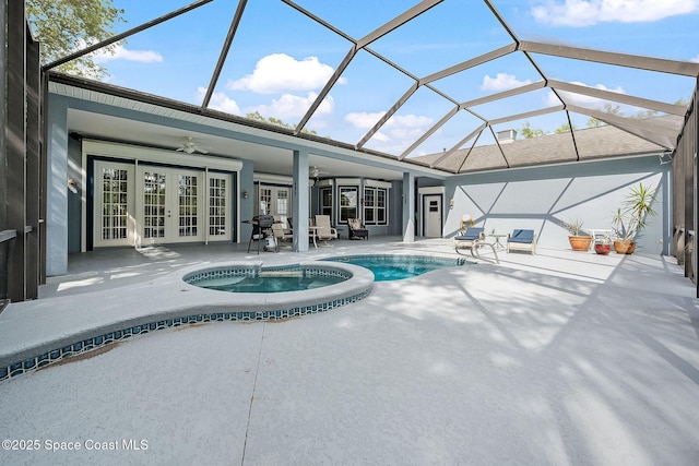 view of swimming pool featuring ceiling fan, a pool with connected hot tub, glass enclosure, a patio, and french doors