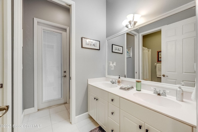 full bath featuring tile patterned floors, double vanity, a sink, and baseboards
