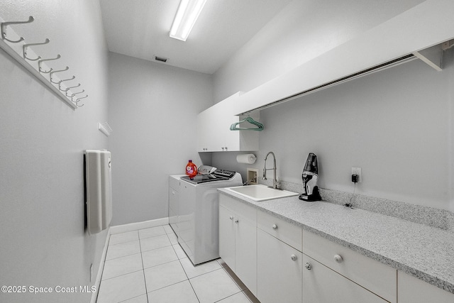 clothes washing area featuring light tile patterned floors, visible vents, washing machine and clothes dryer, a sink, and cabinet space