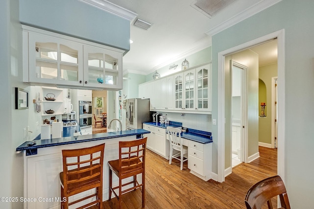 kitchen featuring white cabinetry, ornamental molding, visible vents, appliances with stainless steel finishes, and dark countertops
