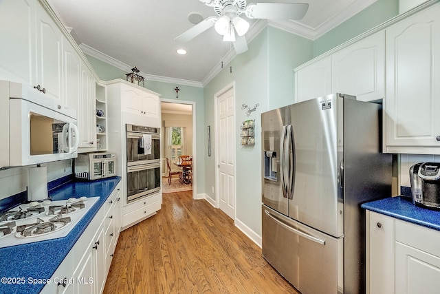 kitchen with crown molding, white cabinets, dark countertops, and stainless steel appliances