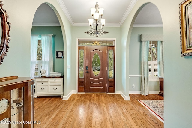 foyer featuring crown molding, light wood finished floors, plenty of natural light, and a notable chandelier
