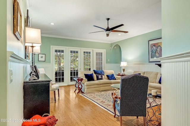 living area featuring wainscoting, a ceiling fan, french doors, and wood finished floors