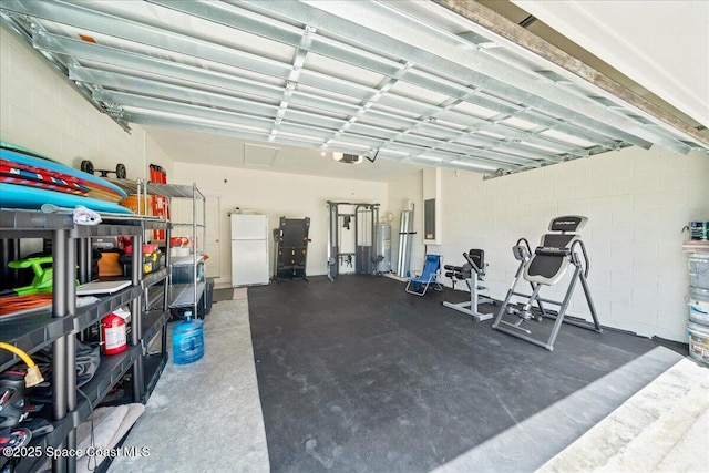 710 Mulberry St, Sebastian, FL 32958 - garage featuring water heater, freestanding refrigerator, a garage door opener, concrete block wall, and electric panel