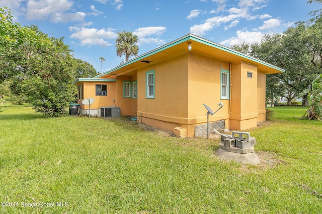 1632 Water Dr NE, Palm Bay, FL 32905 - view of home's exterior with a lawn, an outdoor fire pit, cooling unit, and stucco siding