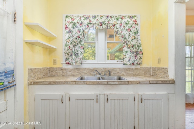 1632 Water Dr NE, Palm Bay, FL 32905 - kitchen featuring white cabinetry, a sink, tile countertops, and a healthy amount of sunlight