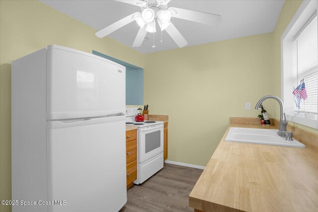 kitchen with light countertops, white appliances, ceiling fan, wood finished floors, and a sink