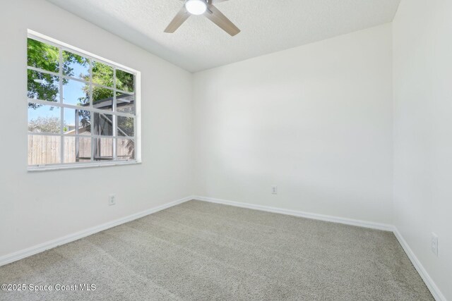 empty room with carpet floors, baseboards, ceiling fan, and a textured ceiling