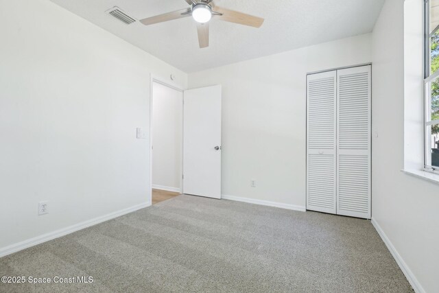 unfurnished bedroom featuring a closet, visible vents, multiple windows, and carpet