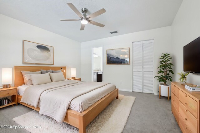 bedroom featuring light colored carpet, connected bathroom, visible vents, a ceiling fan, and a closet
