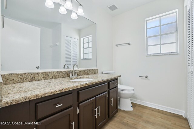 full bath featuring vanity, toilet, baseboards, visible vents, and wood finished floors