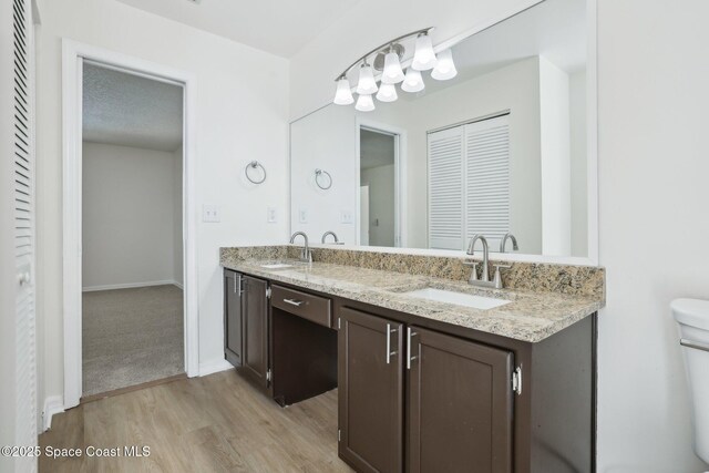 full bathroom featuring double vanity, a sink, toilet, and wood finished floors