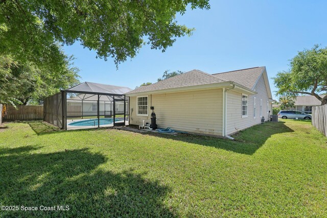 back of house featuring a fenced backyard, a fenced in pool, glass enclosure, and a lawn