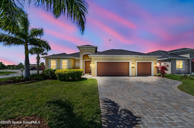 view of front of home with an attached garage, a front lawn, stucco siding, and decorative driveway