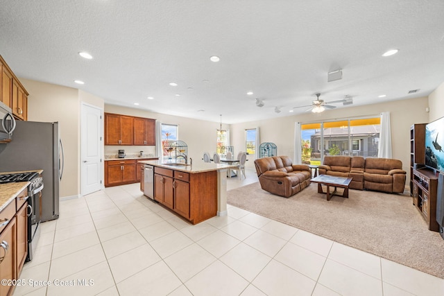 kitchen featuring recessed lighting, a sink, brown cabinetry, appliances with stainless steel finishes, and open floor plan
