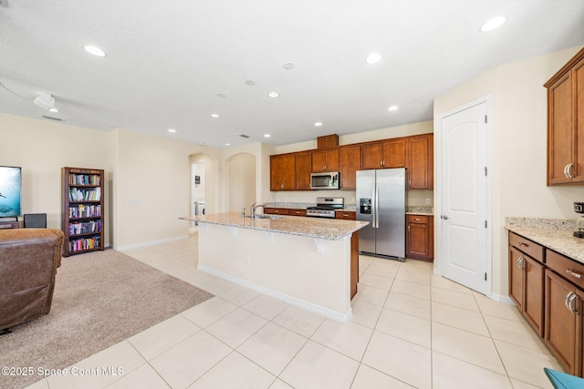 kitchen featuring stainless steel appliances, arched walkways, a sink, open floor plan, and recessed lighting