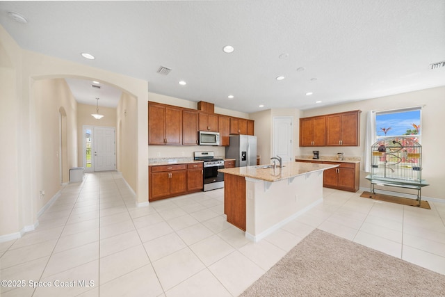 kitchen featuring recessed lighting, a sink, arched walkways, baseboards, and appliances with stainless steel finishes