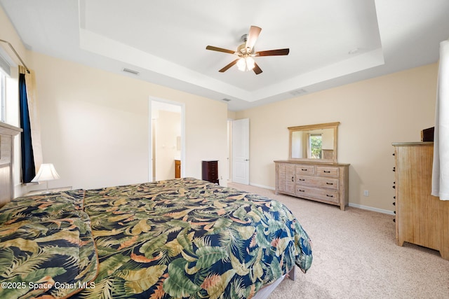 bedroom with a tray ceiling, visible vents, carpet flooring, and baseboards