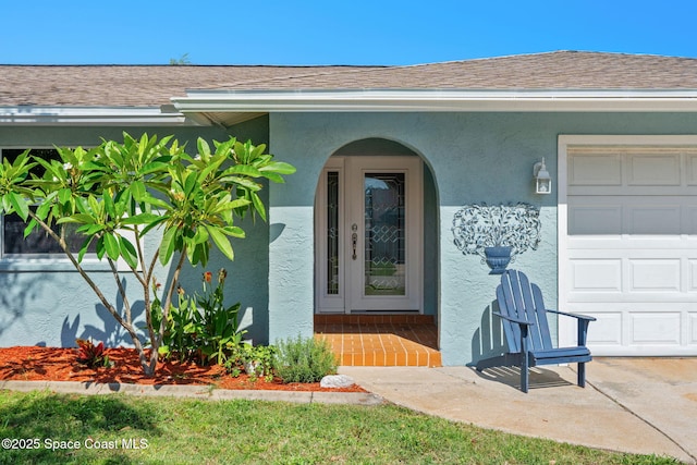 1445 Centaurus Ct, Merritt Island, FL 32953 - view of exterior entry with an attached garage, stucco siding, and roof with shingles