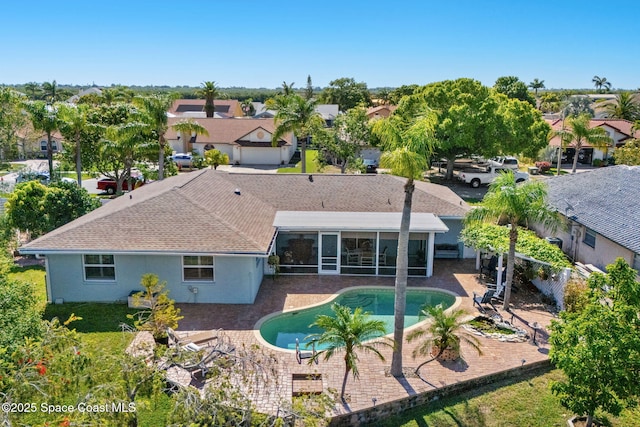 1445 Centaurus Ct, Merritt Island, FL 32953 - rear view of property with a sunroom, a patio area, a residential view, stucco siding, and an outdoor pool