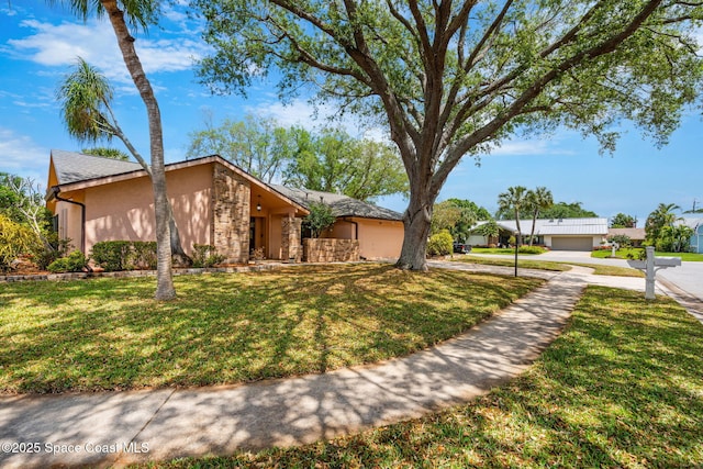 mid-century home featuring driveway, stucco siding, an attached garage, and a front lawn