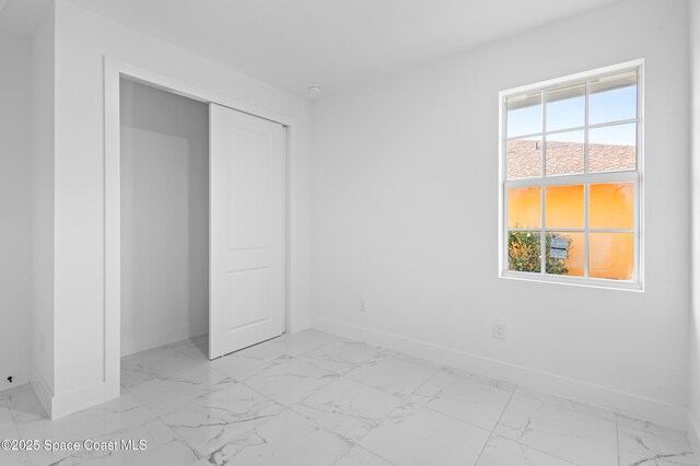 5271 NW Mayfield Ln, Port St Lucie, FL 34983 - unfurnished bedroom featuring marble finish floor, a closet, and baseboards