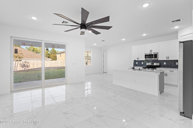 5271 NW Mayfield Ln, Port St Lucie, FL 34983 - kitchen with stainless steel appliances, backsplash, marble finish floor, visible vents, and white cabinets