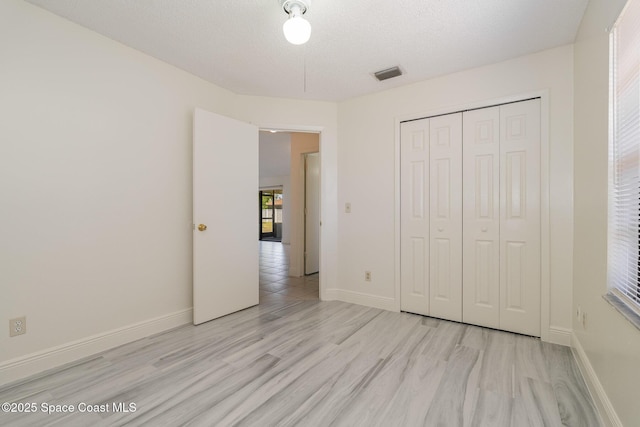 unfurnished bedroom featuring baseboards, visible vents, wood finished floors, and a closet