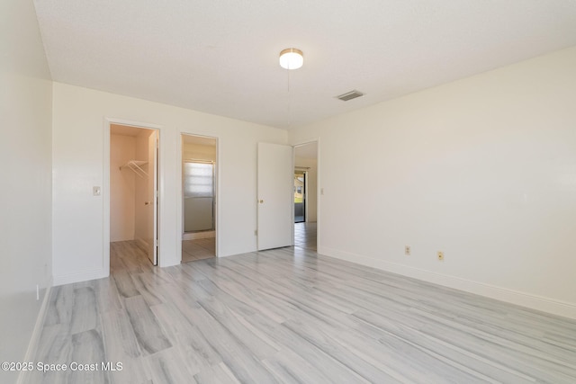 unfurnished room featuring baseboards, light wood-style floors, and visible vents