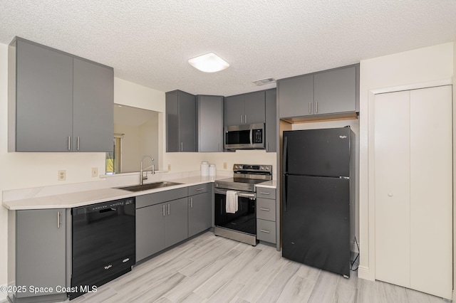 kitchen featuring gray cabinets, black appliances, light countertops, and a sink