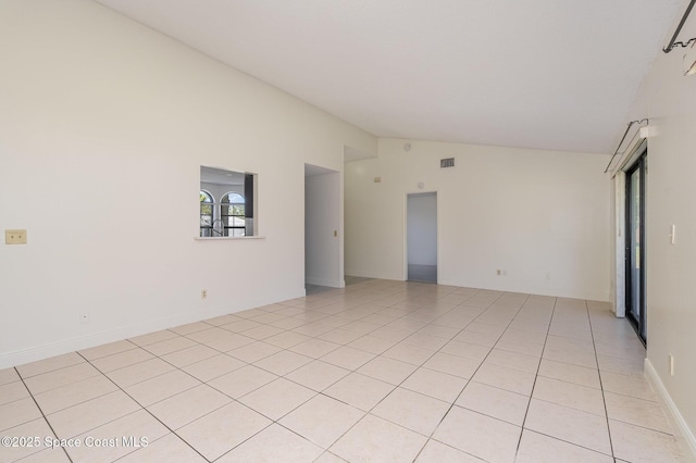 spare room featuring light tile patterned floors, vaulted ceiling, and visible vents