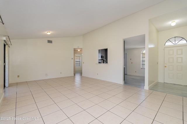interior space with light tile patterned floors, lofted ceiling, and visible vents