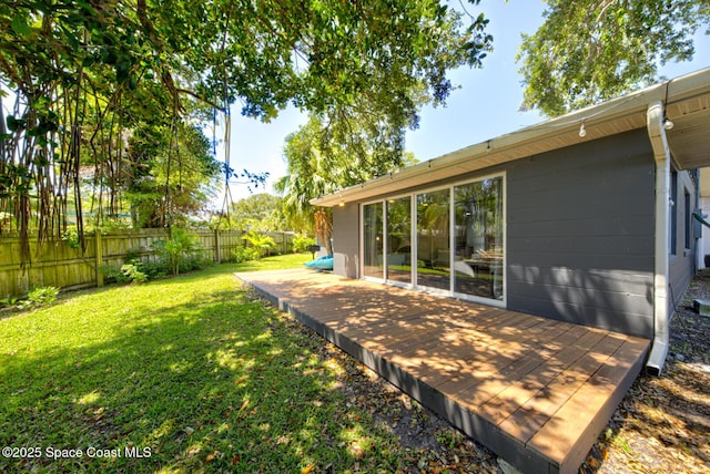 exterior space featuring a fenced backyard, concrete block siding, a yard, and a deck