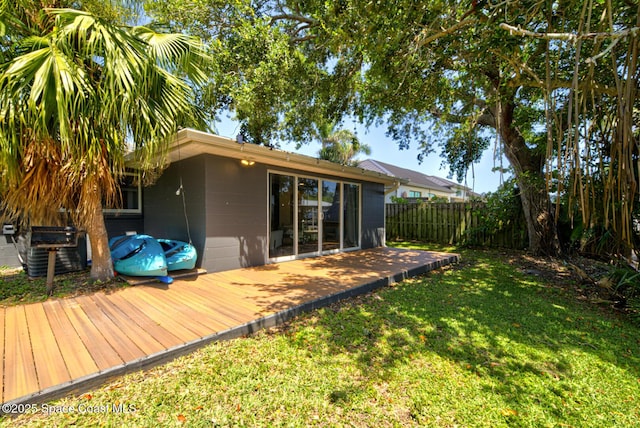 back of property with a deck, fence, cooling unit, a yard, and concrete block siding