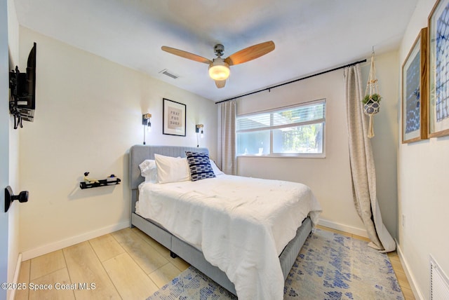 bedroom with light wood-style floors, baseboards, ceiling fan, and visible vents