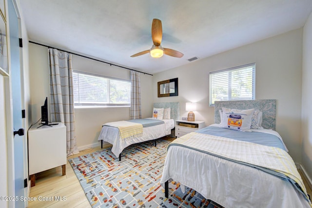 bedroom with visible vents, ceiling fan, wood finished floors, and multiple windows