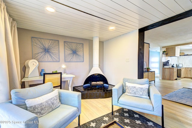 living area with light wood-style floors, wooden ceiling, a wood stove, and recessed lighting